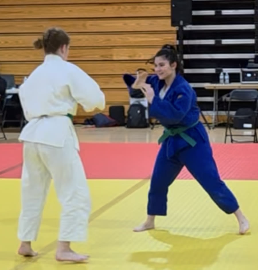 Genevieve Puglissi in a blue gi, squaring off with an opponent at a judo tournament